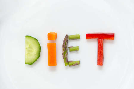 Diet concept. White plate with word - diet - composed of slices of different fruits and vegetableの写真素材