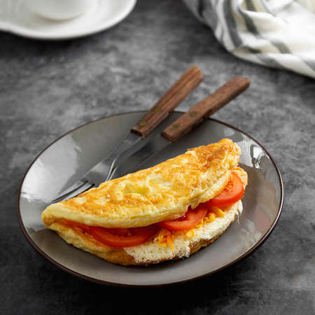 Omelet with cheese and tomatoes. Healthy homemade omelette for breakfast. Dark background.の写真素材