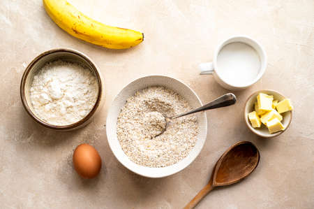 Ingredients for preparing banana cookies and dough on color wooden background