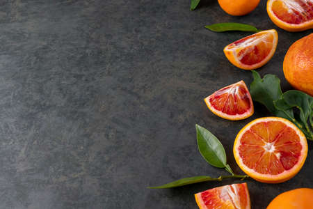 Bloody oranges slices with fresh leaves. Abstract citrus fruit border with copy space.の写真素材
