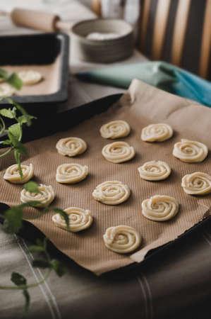 Hands piping butter cookies on baking tray in kitchen.