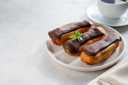 Eclairs with chocolate on white background. Delicious french sweet dessert in a plate, copy space
