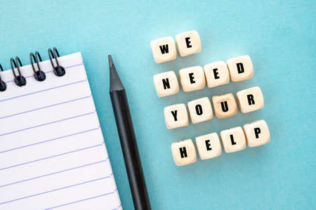 We need your help words written on wooden blocks, abstract blue table to with noteblock and black...