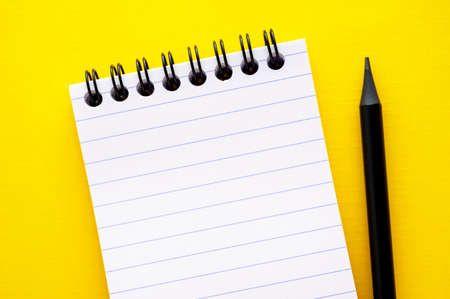 Open, empty blank notebook on a yellow background, spiral notepad on a table. Abstract concept, copy...