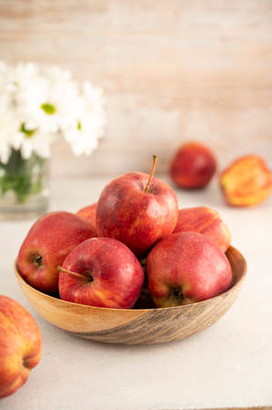 Red apples in bowl on wooden rustic background. Fresh red apple fruits with white flowersの写真素材