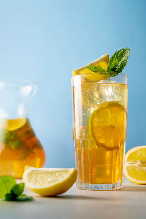 Iced tea with lemon and fresh mint, blue background. Summer backgroundの写真素材