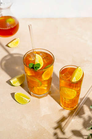 Iced tea with lemon, fresh mint leaves and ice in tall glasses with sun light and shadowの写真素材