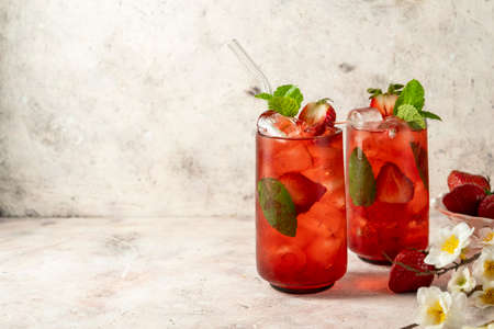 Refreshing strawberry summer drink in glass with ice cubes and mint leaves, copy spaceの写真素材