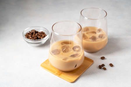 Creamy liqueur in glasses with ice cubes and coffee bean