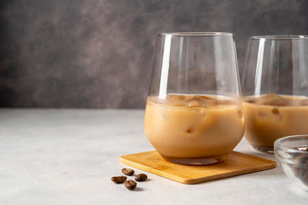 Creamy liqueur in two glasses with ice cubes and coffee beans with copy spaceの写真素材