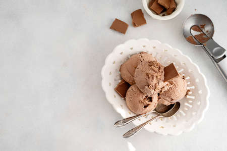 Three brown chocolate ice cream balls, scoops in white bowl over gray background, copy spaceの写真素材