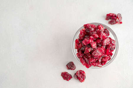 Dried cranberries in glass bowl over bright background, dried fruits concept, top view