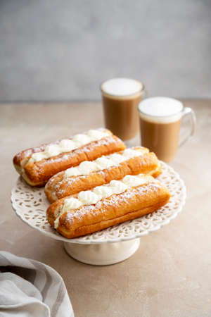 Donut and coffee cups with whipped milk, on warm neutral background. Breakfast food
