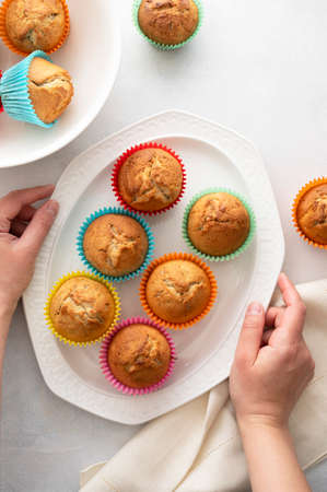 Delicious golden, homemade muffins with colorful paper cups, in a plate on white backgroundの写真素材