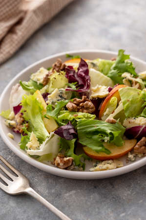 Salad with blue cheese, apples, arugula and nuts with spicy dressing on a grey background. Healthy foodの写真素材