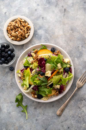 Salad with blue cheese, apples, arugula and nuts with spicy dressing on a grey background. Healthy foodの写真素材