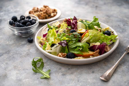Salad with blue cheese, apples, arugula and nuts with spicy dressing on a grey background. Healthy foodの写真素材