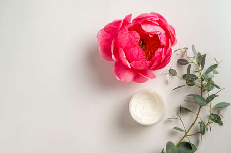 Natural cosmetics concept. A jar of face cream with pink peony flower and eucalyptus, bright backgroundsの写真素材