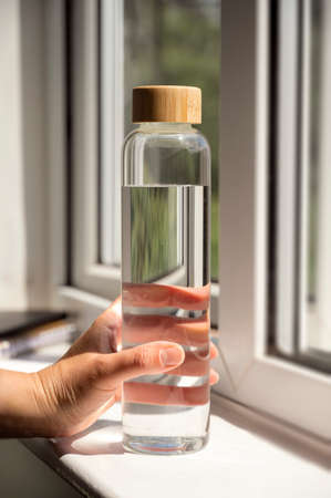 Glass water bottle with wooden lid, hush shadows, drinking water and healthy lifestyl concepts