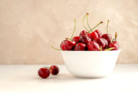 Fresh red cherries in white bowl, on neutral background. Summer delicious fruits