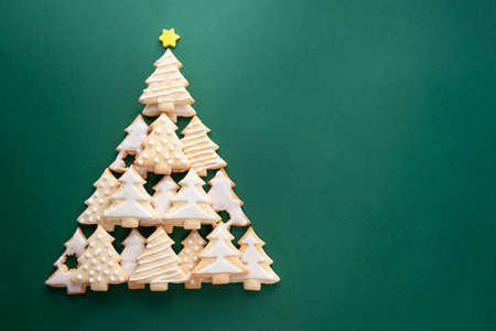 Christmas tree made from christmas tree shaped cookies on green background with copy space for textの写真素材