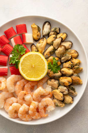 Fresh seafood ingredient - shrimps, mussels and crab sticks in plate, bright background, top view