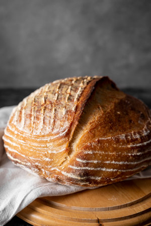 Homemade sourdogh whole round bread on dark background. Home baking concept
