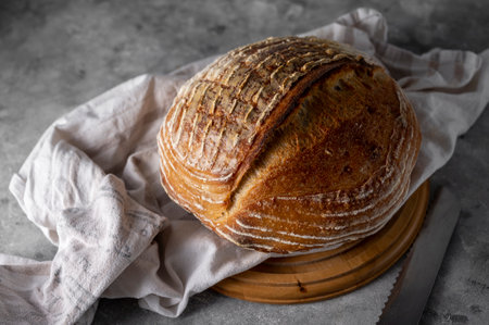 Homemade sourdogh whole round bread on grey background. Home baking concept