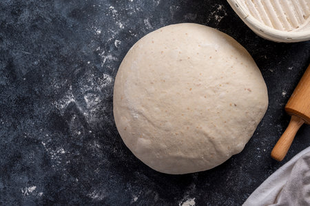 Raw sourdough, dough for homemade baking bread or pizza on dark backgroundの写真素材