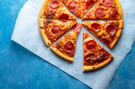 Pepperoni pizza sliced, on blue background, one pizza, top view.の写真素材