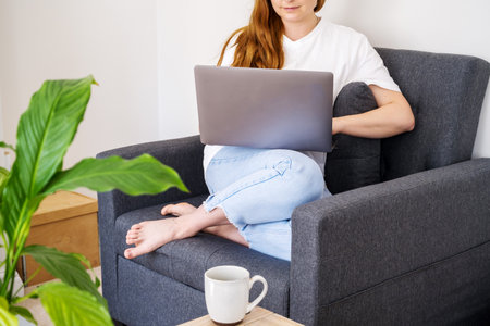 Woman working online, sitting in armchair and using laptopの写真素材
