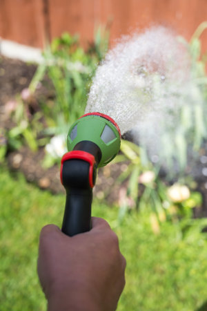 Male hand with hose and water jet watering the gardenの写真素材
