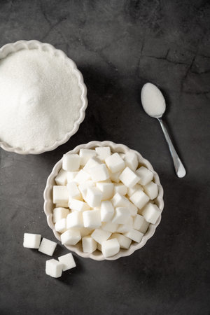 White sugar cubes, in a white bowl, dark background. Top viewの写真素材