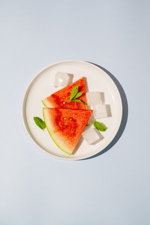 Watermelon triangle slices in a plate blue backgroundの写真素材