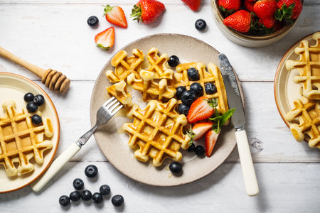 Belgian homemade waffles with strawberries, blueberries and honeyの写真素材