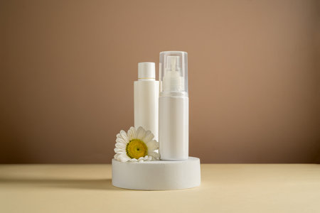 White blank cosmetic bottles with a daisy flower. Natural cosmetics, neutral backgroundの写真素材