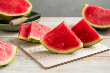 Slices of fresh watermelon on bright rustic wooden table.の写真素材