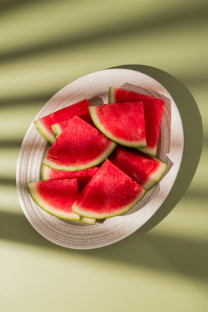 Slices of fresh watermelon in a oval plate, green abstract backgroundの写真素材