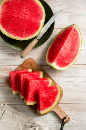 Slices of fresh watermelon on bright rustic wooden table.の写真素材