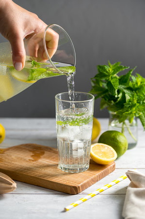 Lemonade with lemons, limes and fresh mint. Pouring homemade lemonade in a glassの写真素材
