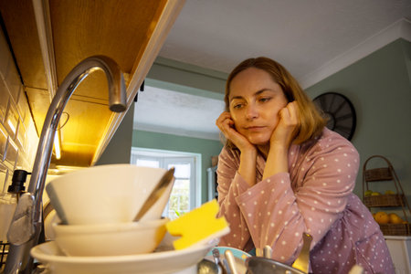 Procrastination, dirty dishes in kitchen, sad woman in the backgroundの写真素材