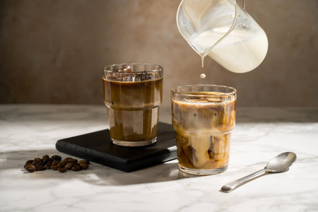 Pouring milk in glass with coffee, refreshing energy coffee drinks