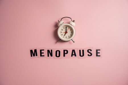 Word Menopause with alarm clock, flat lay, pink backgroundの写真素材