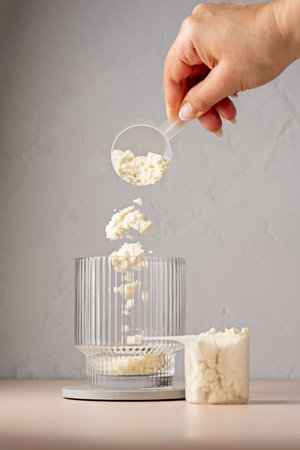 Pouring vanilla protein powder in a glass. Food supplement