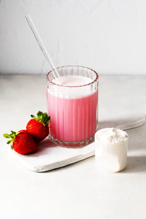 Pink strawberry protein drink shake, and protein powder in a scoop.の写真素材