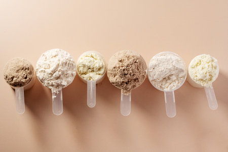 Protein powder in scoops. Different flavours of whey protein powder, top view, copy space