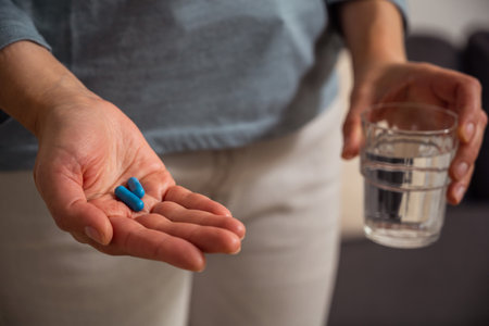 Woman holding blue pills in hand. Health care, dietary supplements, treatment of depression and diseasesの写真素材
