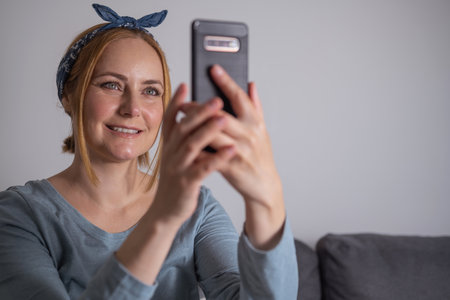 Middle aged millennial woman holding smartphone, social media, communication and modern technologyの写真素材