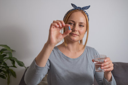 Middle age woman holding a blue pill with fingers .Health care, dietary supplements, treatment of depression and diseasesの写真素材