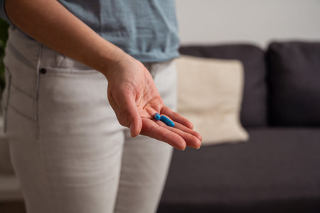 Woman holding blue pills in hand. Health care, dietary supplements, treatment of depression and diseasesの写真素材